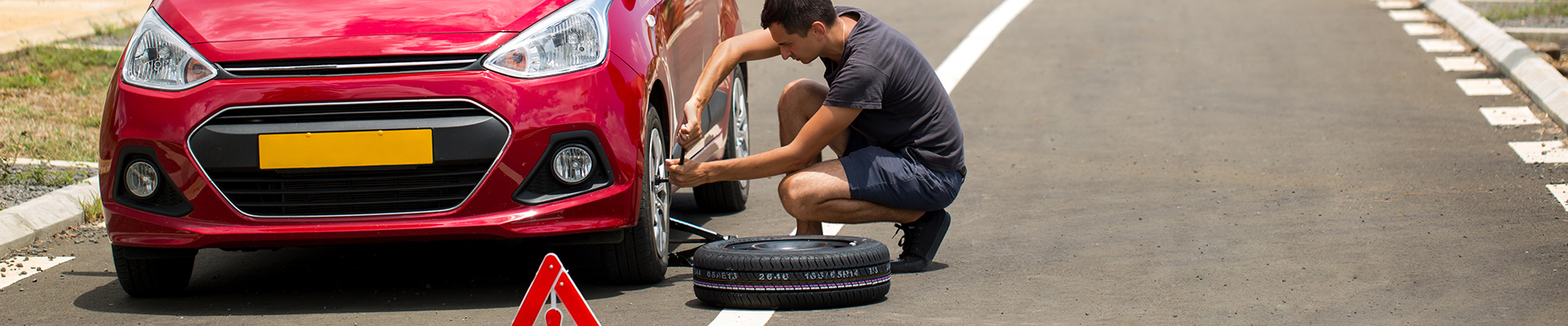 Mann wechselt einen Reifen an seinem PKW